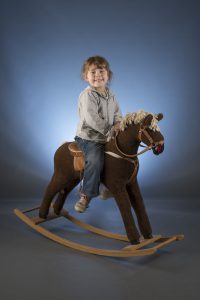 Enfant sur cheval à bascule sur fond coloré